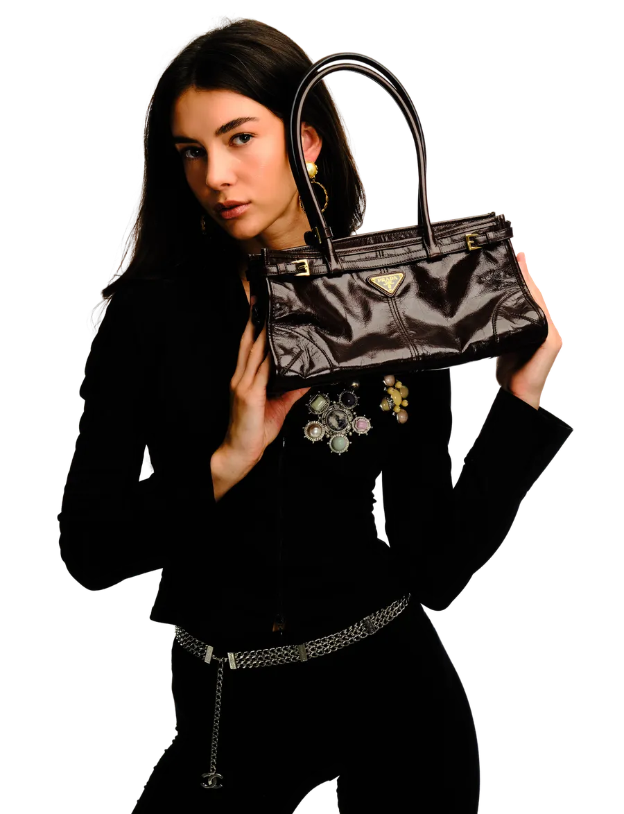 Model holding a Prada leather handbag with statement brooch and chain belt