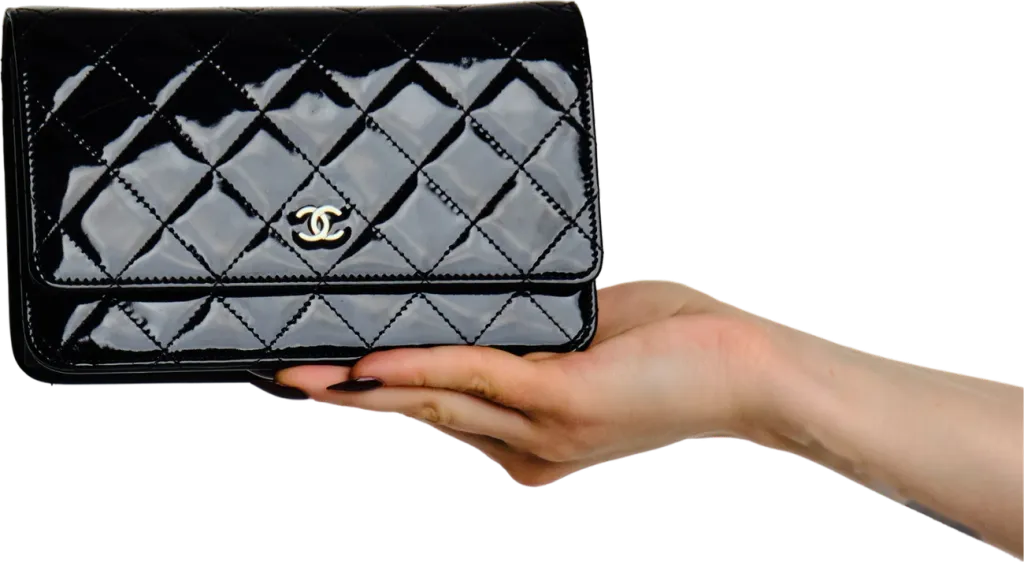 Chanel patent wallet on chain held out in a hand